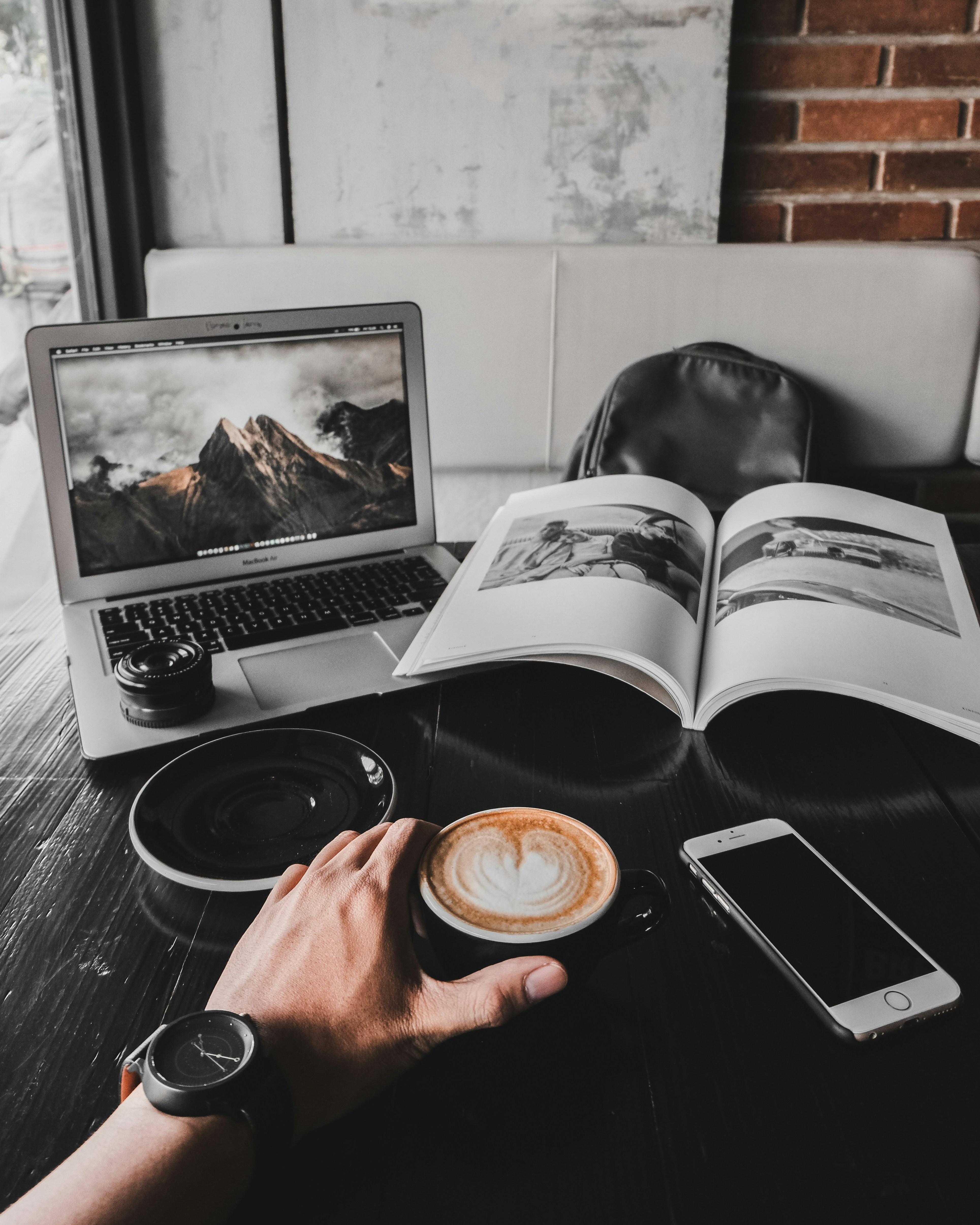 Laptop con foto de montaña, libro de fotografía y café en una mesa · Photo: Unsplash