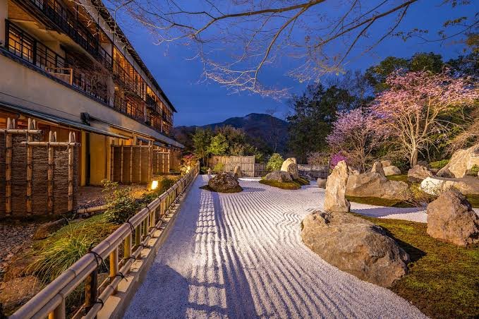 Jardín de piedra iluminado en un ryokan de Hakone, entre cerezos en flor