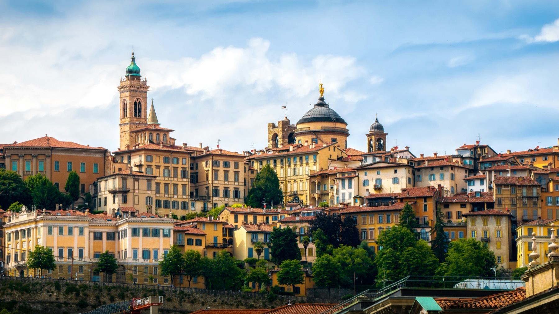 Callejón empedrado de Bérgamo Alta al amanecer, con las murallas venecianas y la niebla de la llanura lombarda