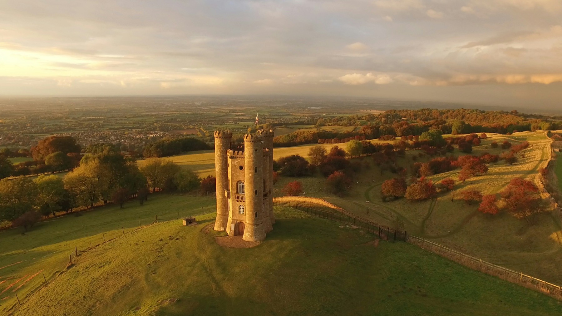 Pueblo de piedra dorada en los Cotswolds con jardines en flor y una carretera de campo vacía