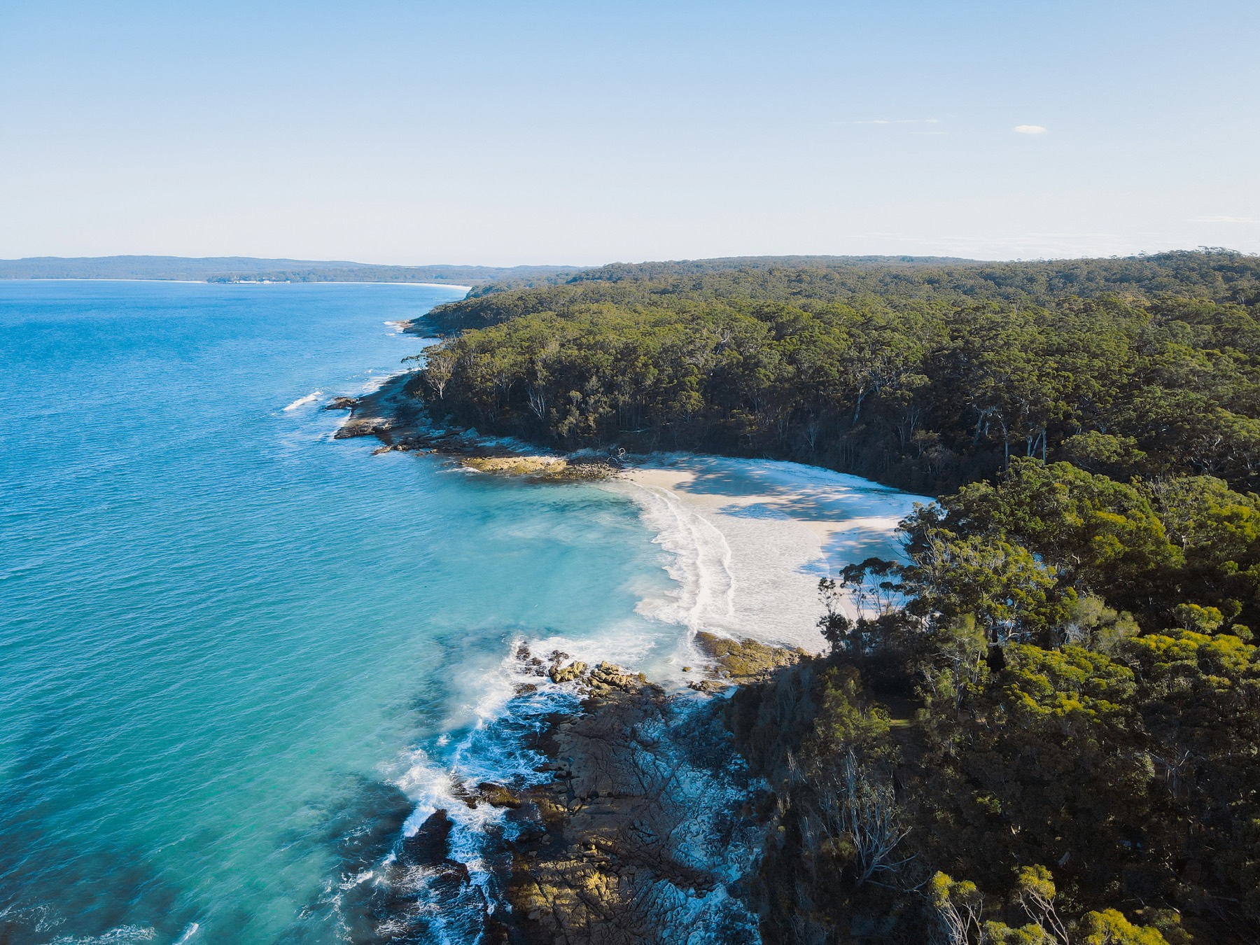 Arena blanca y agua turquesa de Hyams Beach al amanecer, sin figuras humanas, Booderee National Park de fondo